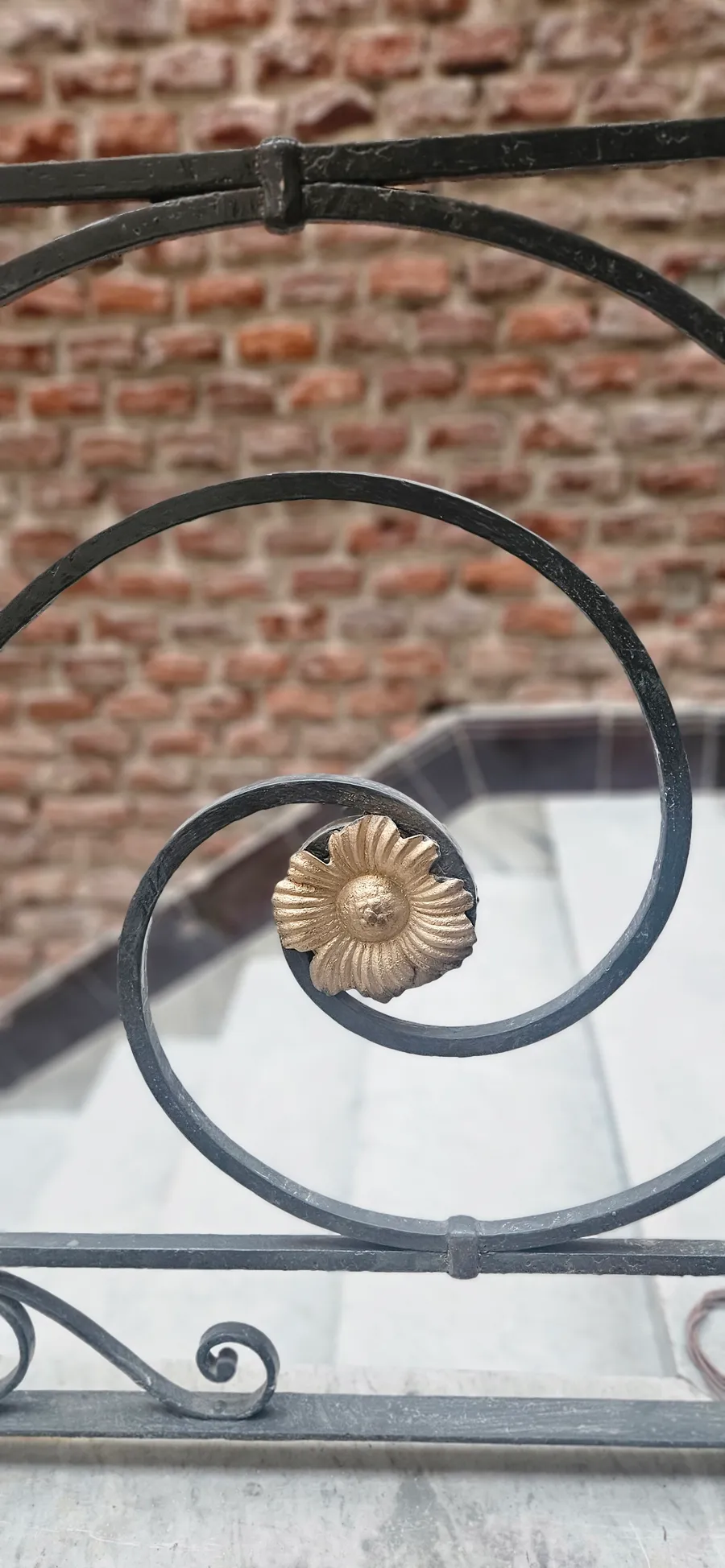 Detalle de la herrería original de la baranda, con roseta de bronce, sobre muro de ladrillo